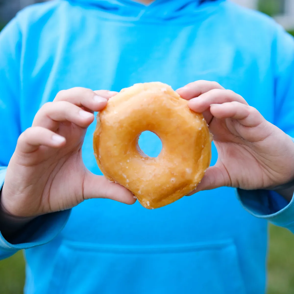 Happy customer enjoying a glazed donut from Michaels Bakery